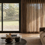 Modern living room with a large window, curtains, and a sofa.