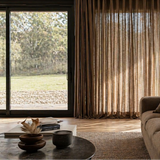Modern living room with a large window, curtains, and a sofa.